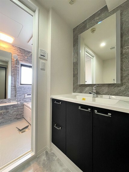 石目調の壁・床とブラックの洗面台の組み合わせが、ラグジュアリーな印象をもたらし、清潔感を漂わせます。