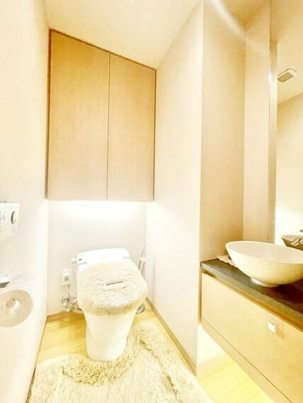 【トイレ】手洗いカウンターのついた清潔感のあるトイレ。背面の収納棚は収納力はもちろん下部に照明を設置しており、すっきりかつ上質な雰囲気を醸します。