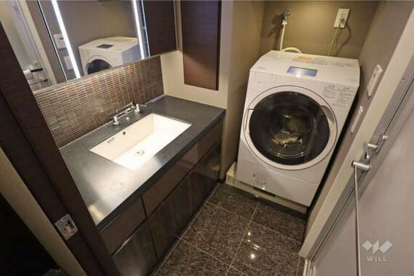 洗面室はワイドタイプ、三面鏡になっているため収納量も豊富です。洗濯機の上には収納スペースもございます。