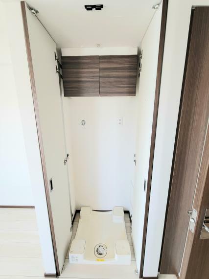 洗濯機置き場は扉が付いていて収納可能です。上部には吊戸棚が付いていて洗剤等を収納するのに便利です