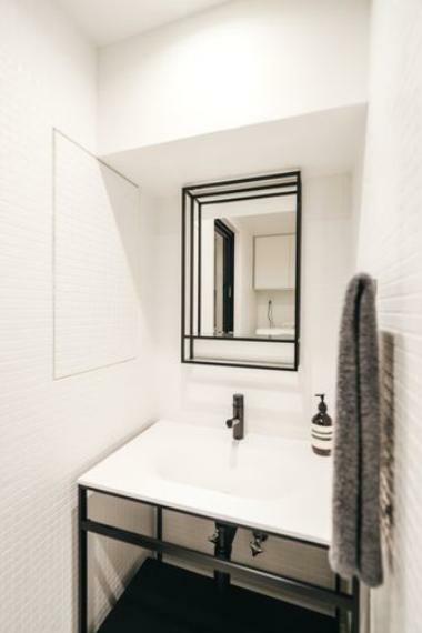 洗面:室内とは異なり白を基調とした明るいトーンで仕上げた水周り。壁は高級感のあるタイル張りです。