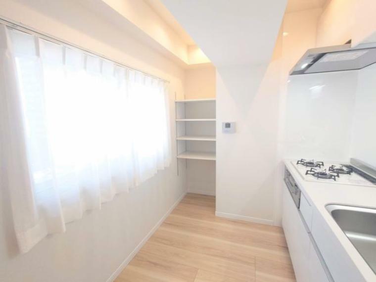キッチンのサイドに収納棚を設置。窓のあるキッチンは、明るく換気もしやすい配置です。