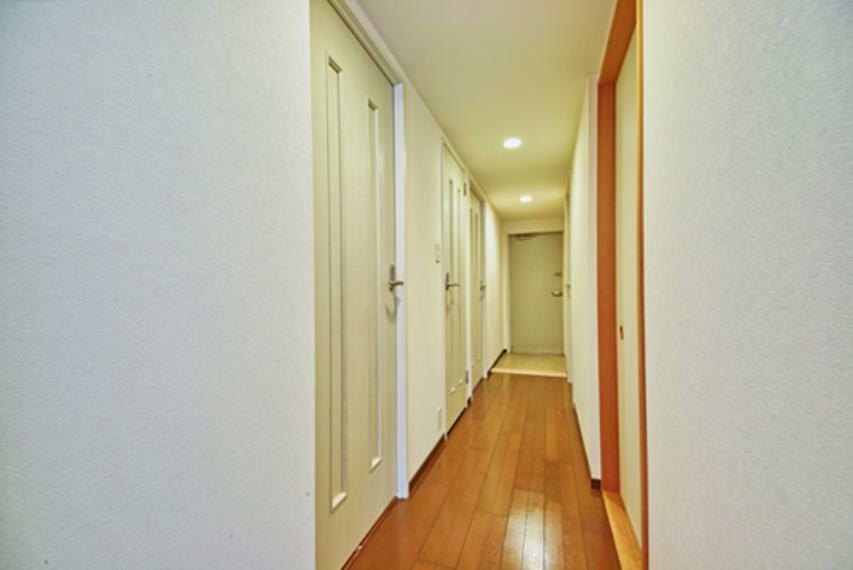 玄関からリビングに続く廊下。柔らかい色のフローリングと清潔感のあるクロスが明るい雰囲気を演出します。