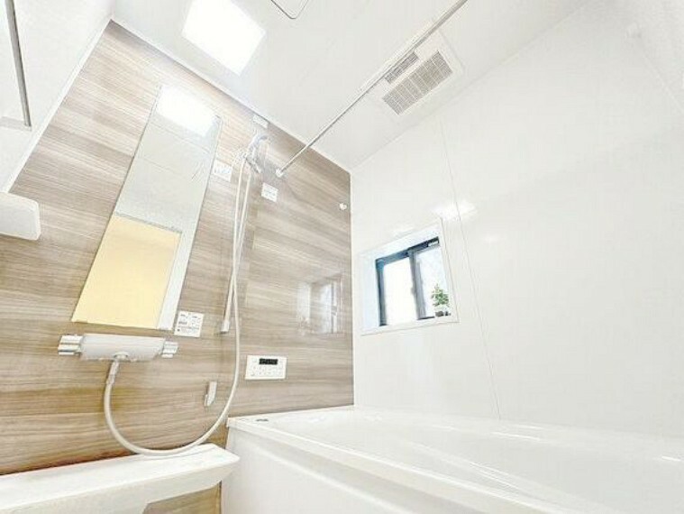 窓から自然光が届く明るい浴室。追焚・浴室乾燥機付き。