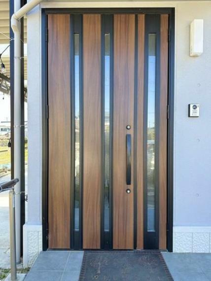 木目×ブラックフレームの落ち着いたデザインの玄関が家の外観を引き締めています。