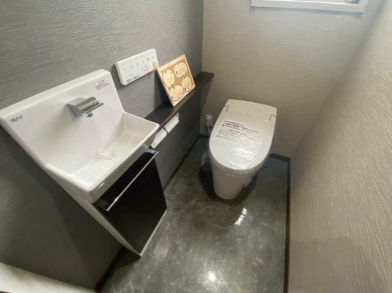 シンプルで機能的なミニ手洗い場付カウンターのあるトイレ。ウォシュレット付。