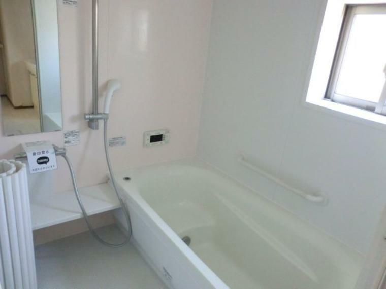 薄く淡いピンクの浴室壁。ゆったりくつろげるバスタブ。