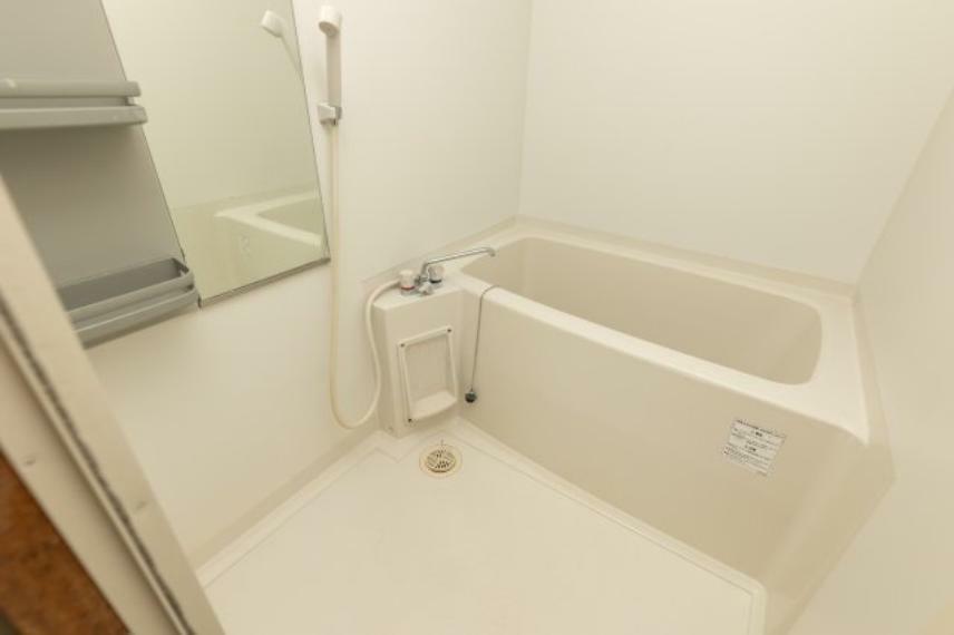 白色で統一されたきれいで清潔感のある浴室。シャワー、棚、鏡がついており、湯はり機能があります。浴槽につかれば一日の疲れも吹き飛びそうです。窓はありませんが、換気扇があるので湿気がこもりにくいですよ。