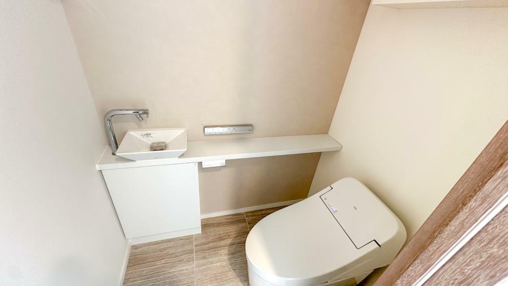 手洗いカウンター付きウォシュレットトイレ。小物類やストックなどもしまえる収納付き。室内（2024年4月）撮影