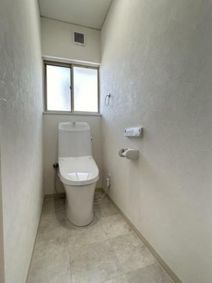「一階トイレ」白色の床と窓から差し込む光で明るい印象のちれです。二階にもトイレがございます。